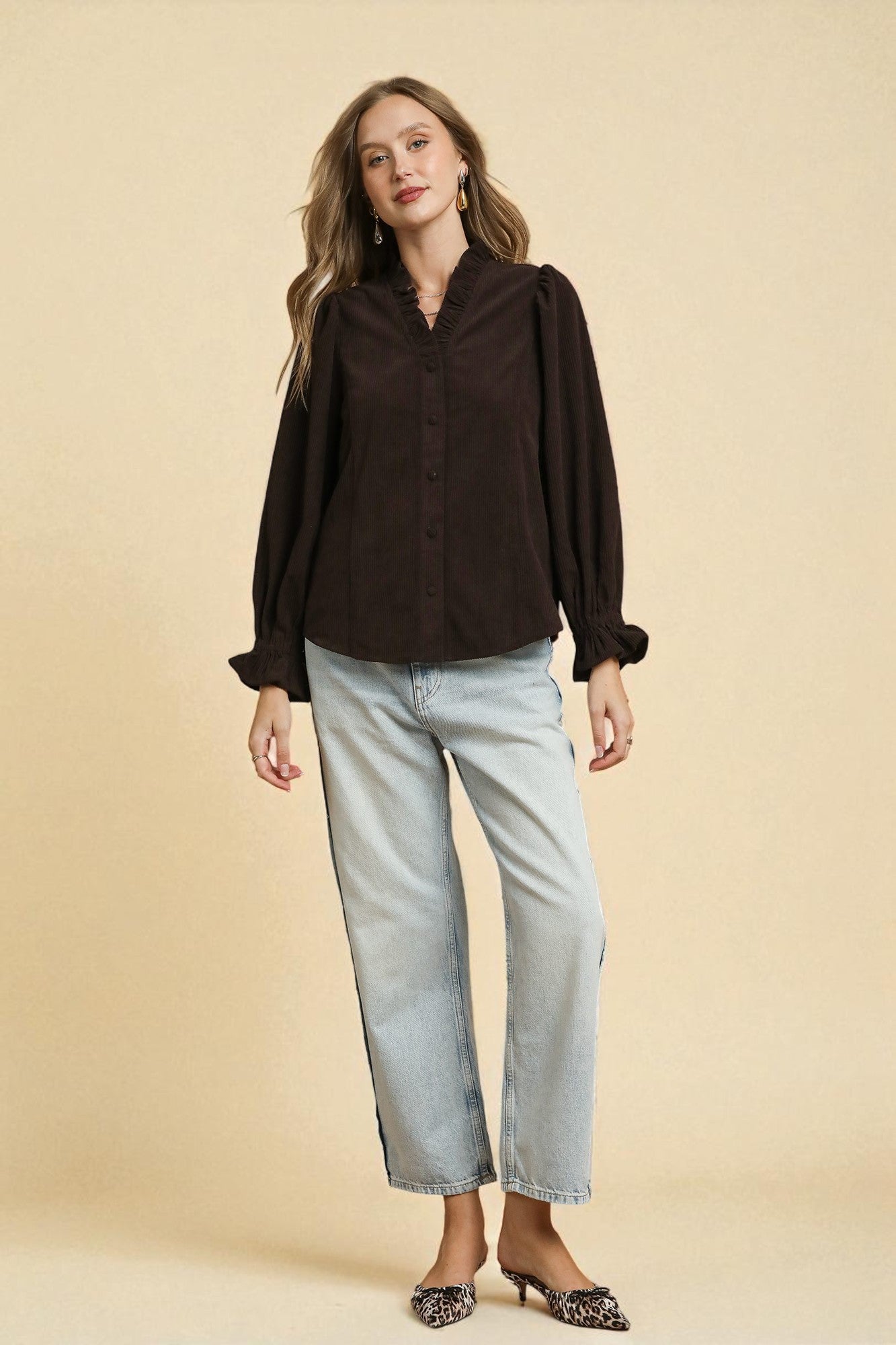 Woman wearing a brown blouse and light blue jeans on a beige background