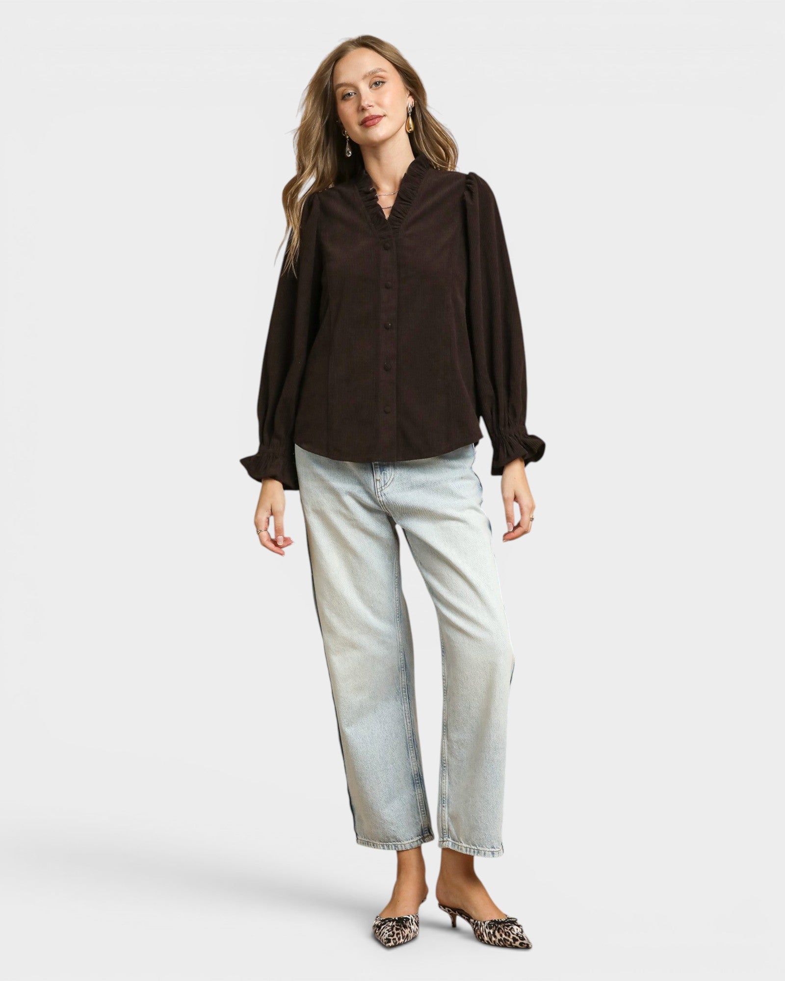 Woman wearing a brown blouse and light blue jeans on a white background