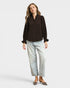 Woman wearing a brown blouse and light blue jeans on a white background