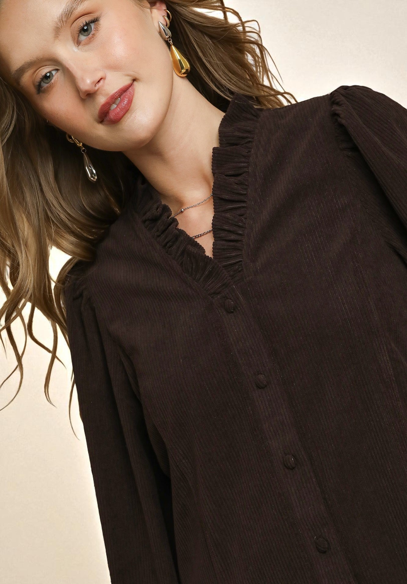 Woman wearing a dark brown blouse with a neutral background