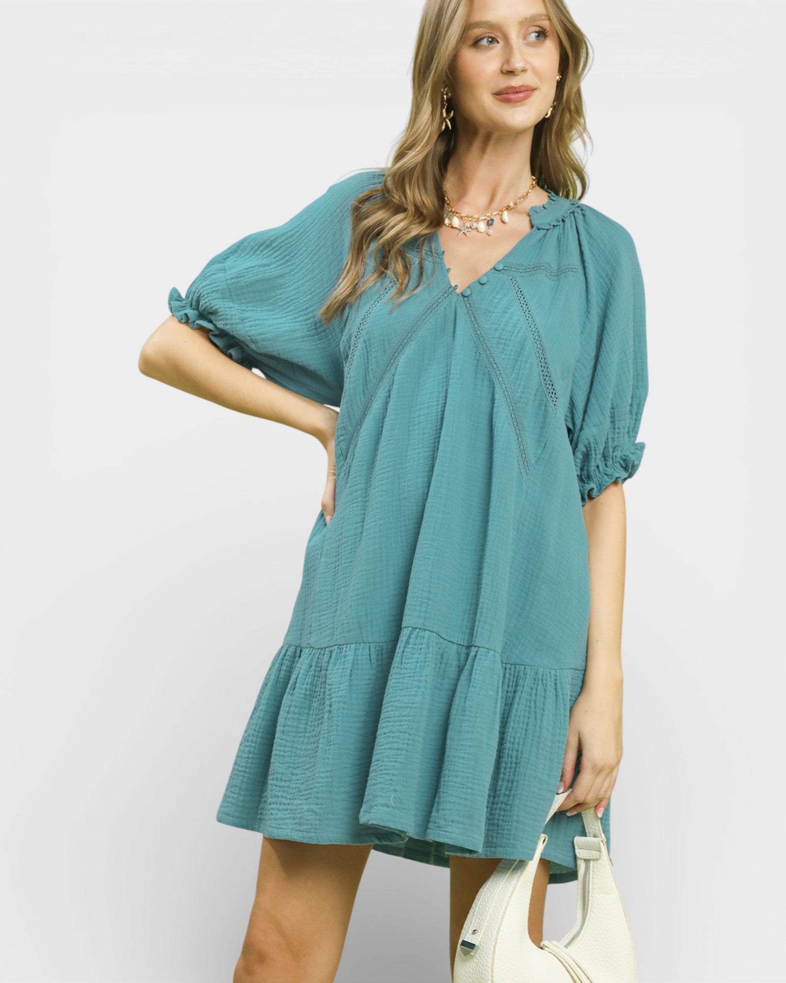 Woman wearing a teal dress with a plain background