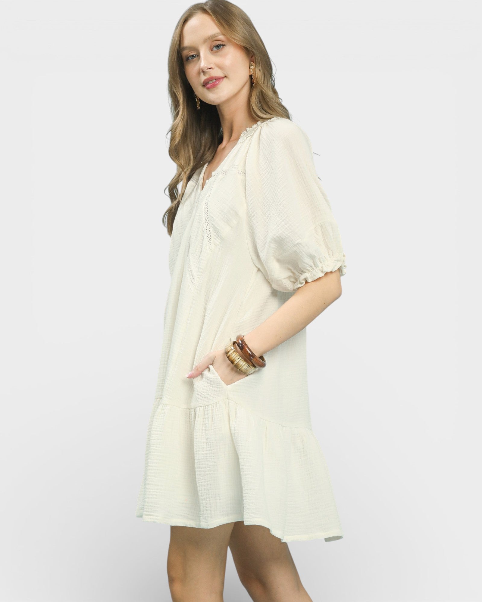 Woman wearing a light-colored dress with a plain background