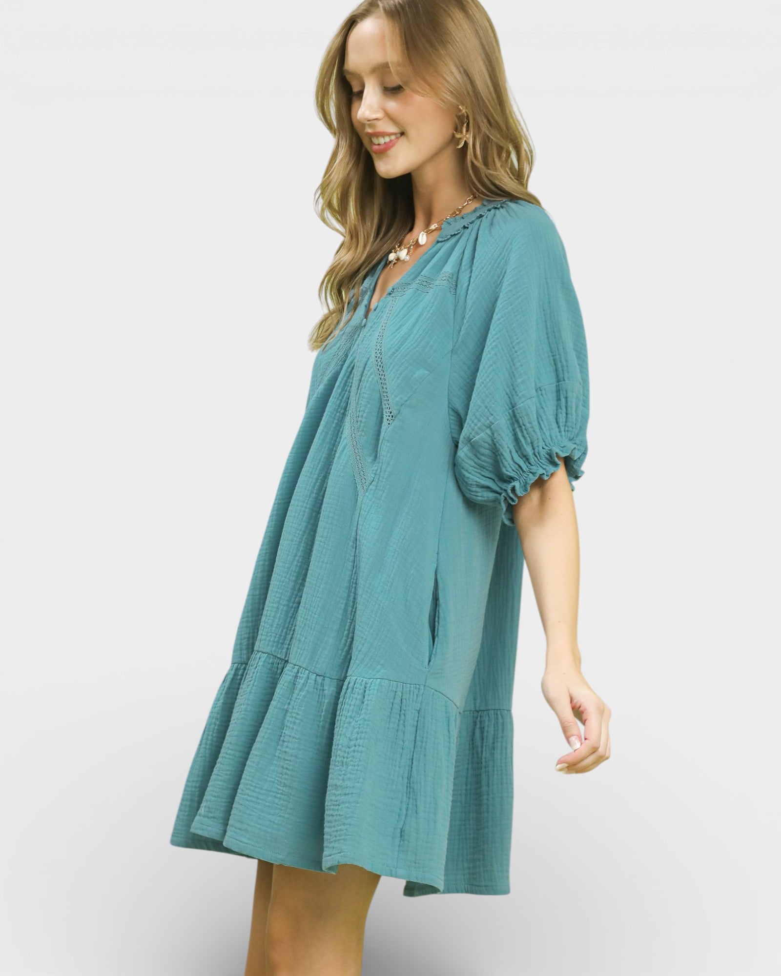 Woman wearing a teal dress with puff sleeves on a white background