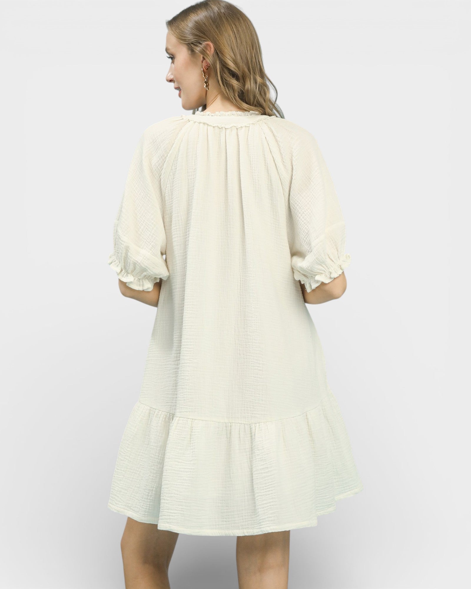 Woman wearing a light-colored dress on a plain background