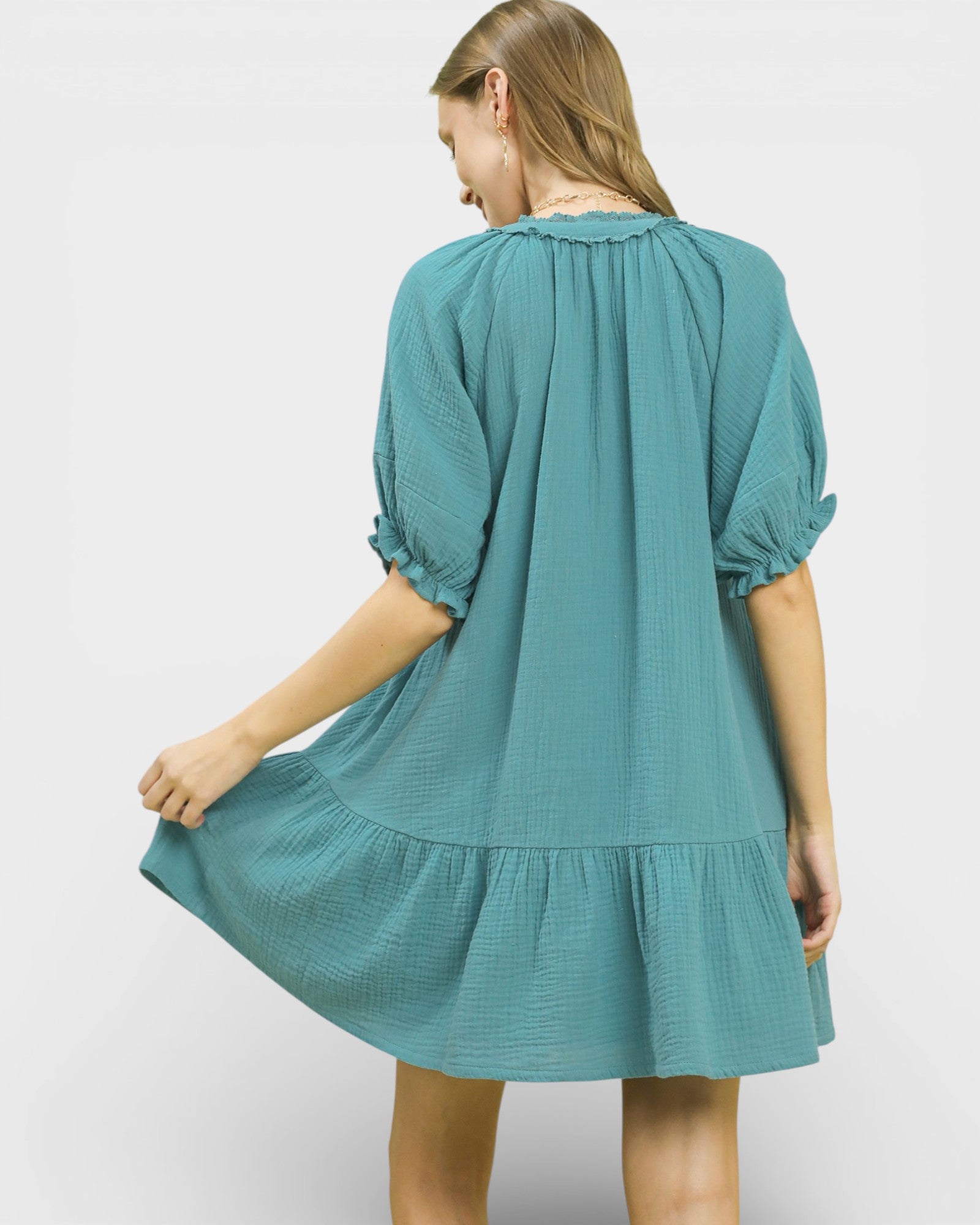 Woman wearing a teal dress with puff sleeves on a white background