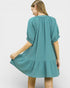 Woman wearing a teal dress with puff sleeves on a white background