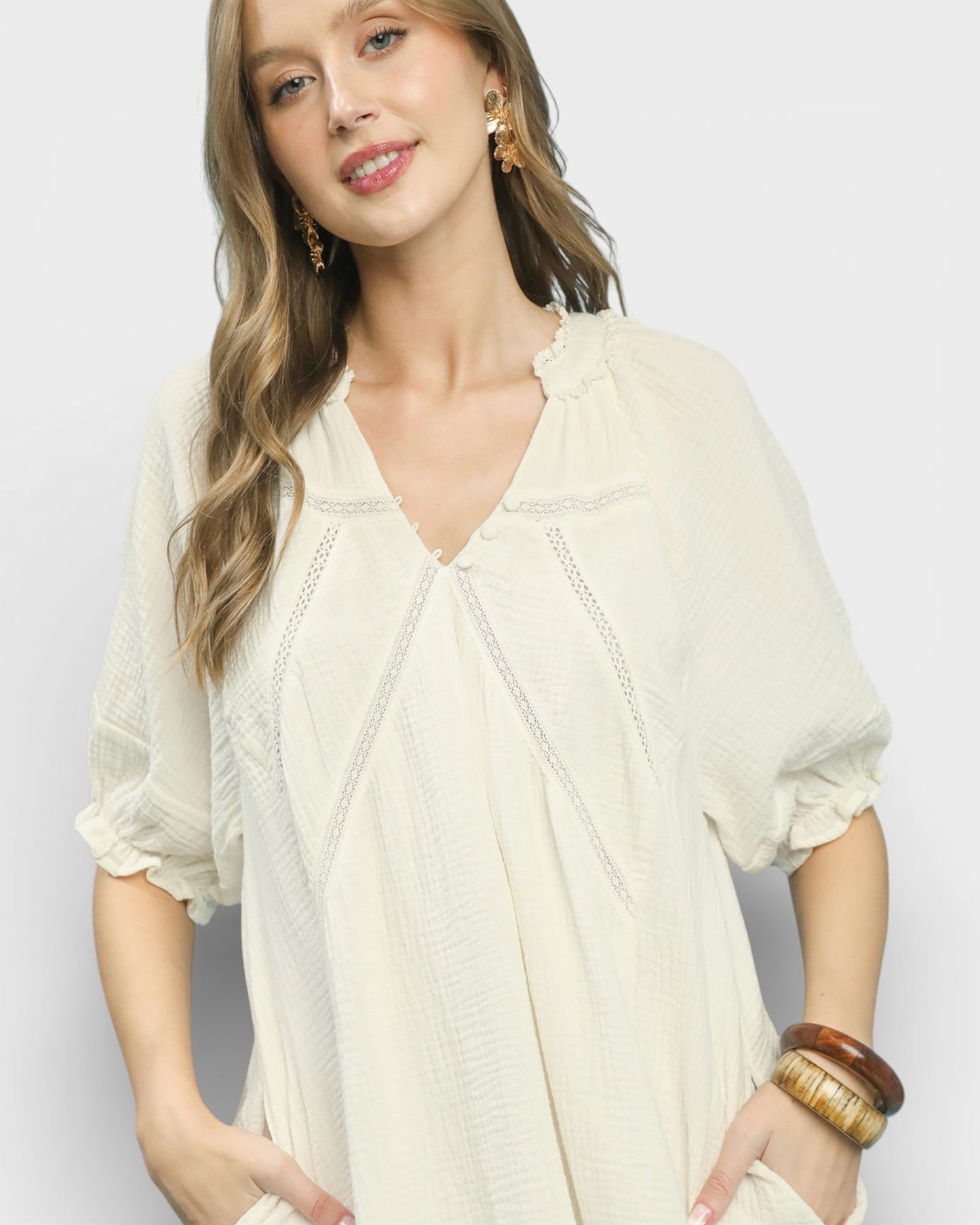 Woman wearing a light-colored blouse with a plain background