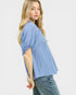 Woman wearing a light blue top and jeans on a white background