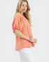 Woman wearing a coral blouse with puff sleeves on a white background