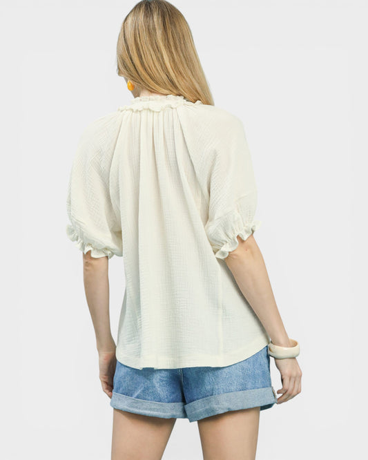 Woman wearing a white blouse and blue shorts on a plain background