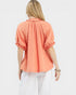 Woman wearing a coral blouse with puff sleeves on a white background