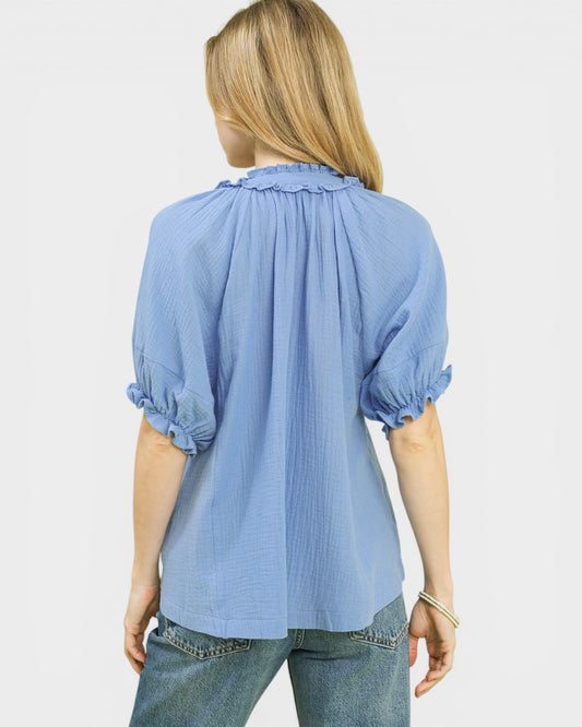 Woman wearing a light blue blouse with balloon sleeves on a white background