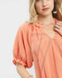 Woman wearing a peach-colored blouse with lace details on a white background