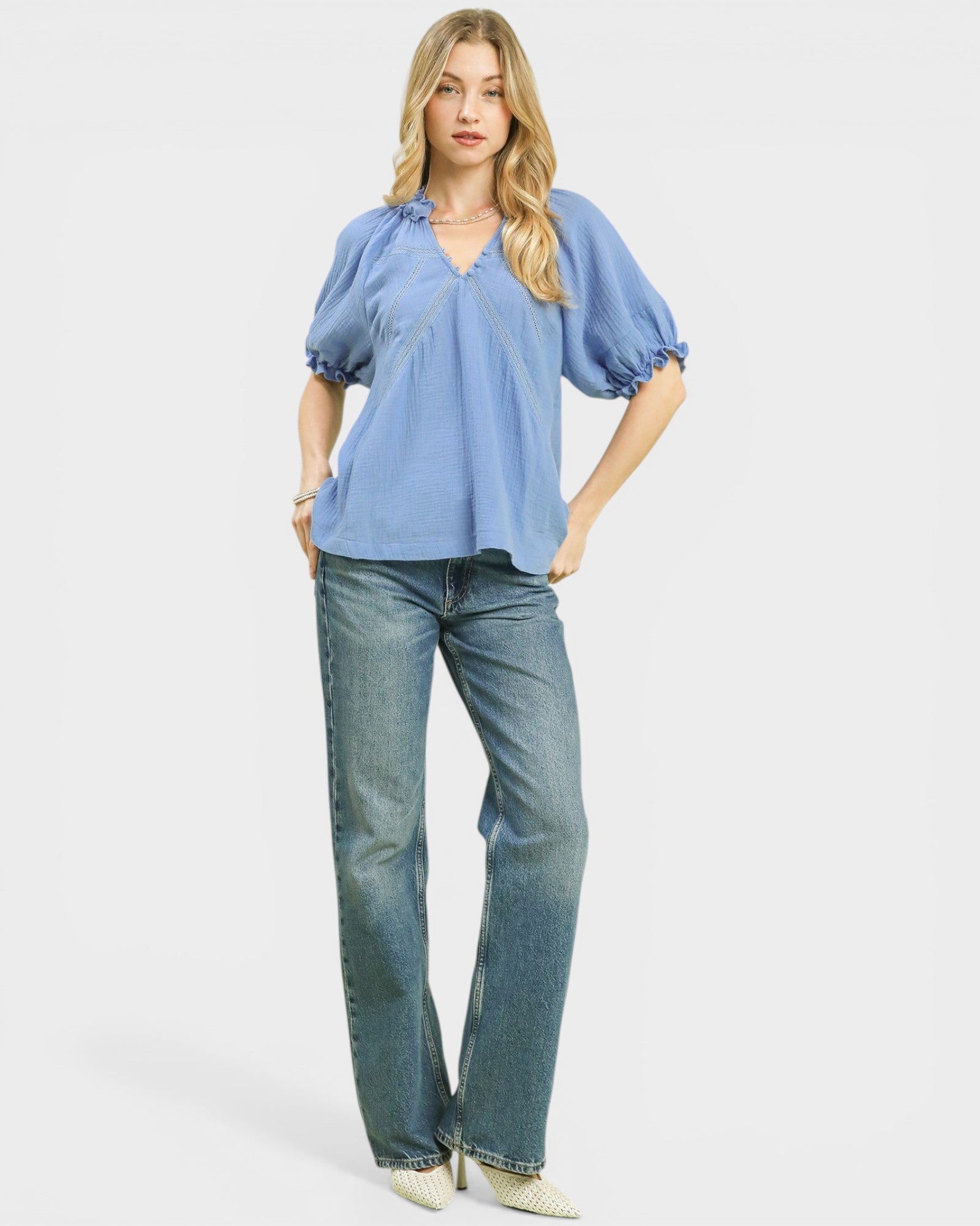 Woman wearing a blue blouse and jeans on a white background