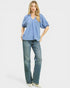 Woman wearing a blue blouse and jeans on a white background