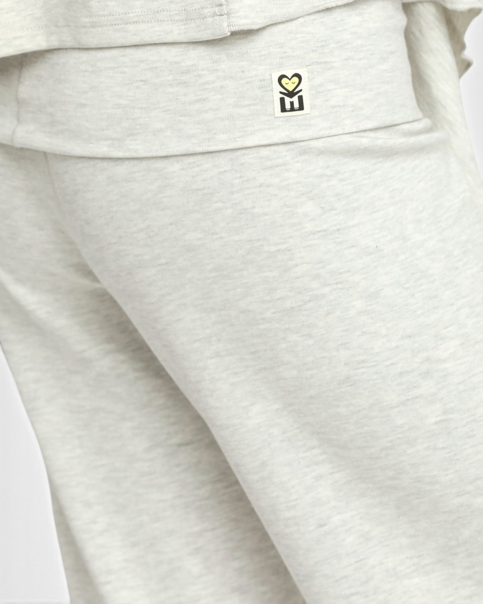 Close-up of light heather gray sweatpants showing the side pocket with a small black and yellow tulip logo.