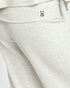 Close-up of light heather gray sweatpants showing the side pocket with a small black and yellow tulip logo.