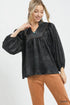 Woman wearing a black blouse with a collar and brown pants on a white background