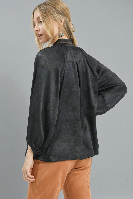 Woman wearing a dark gray top and brown pants on a gray background