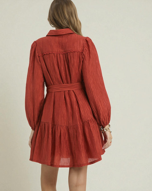 Red pleated dress worn by a person on a beige background