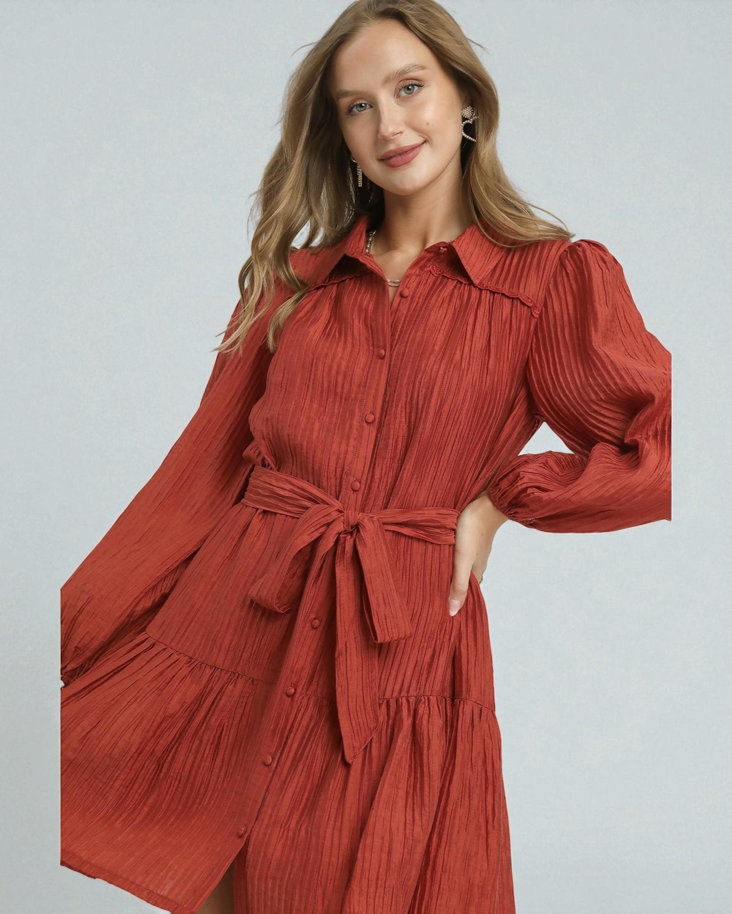 Woman wearing a red pleated dress on a light gray background