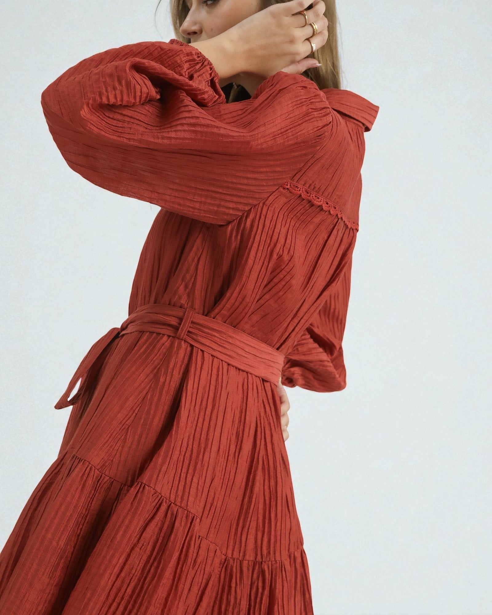 Red pleated dress worn by a person on a white background