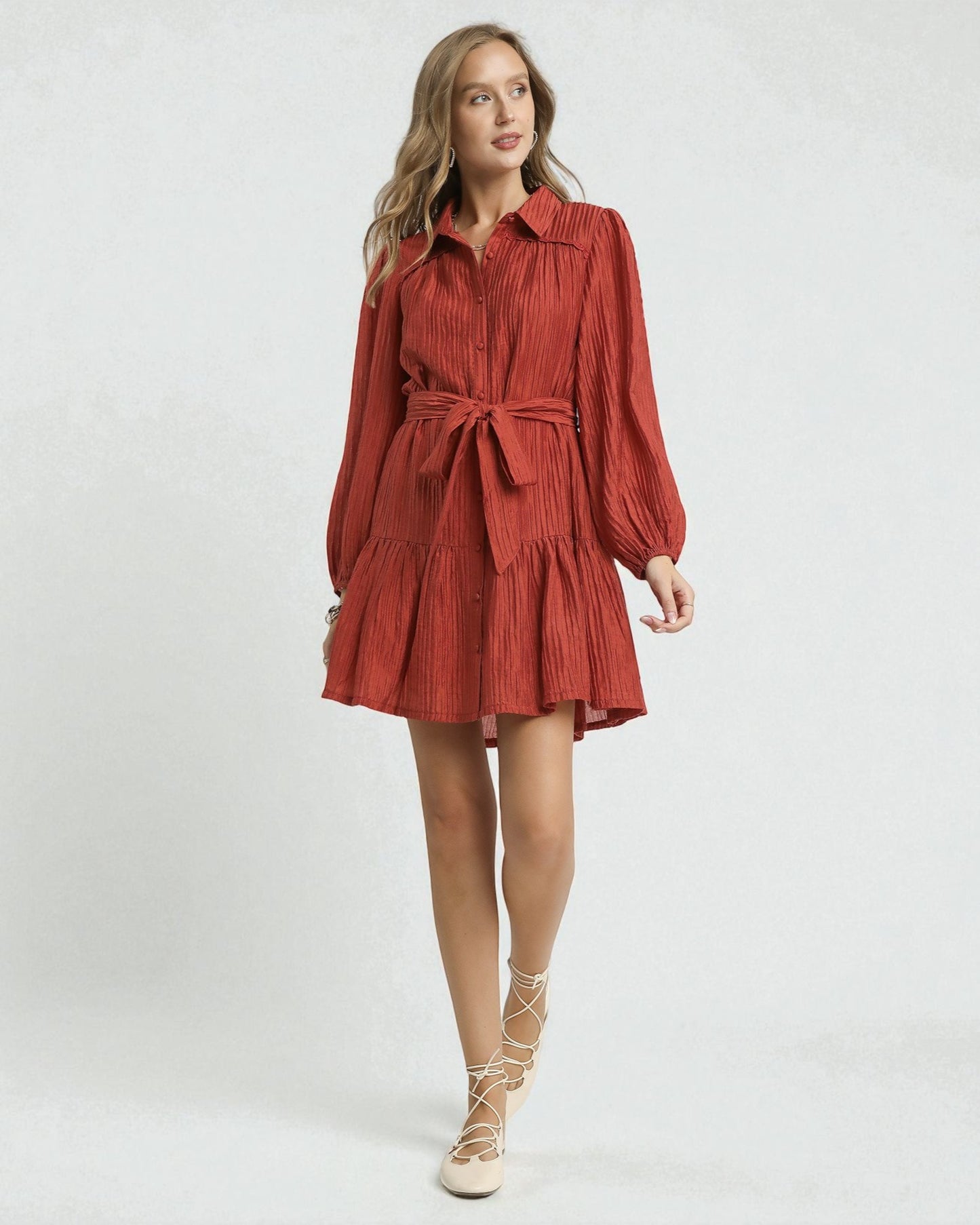 Woman wearing a red dress with long sleeves and a belt on a white background