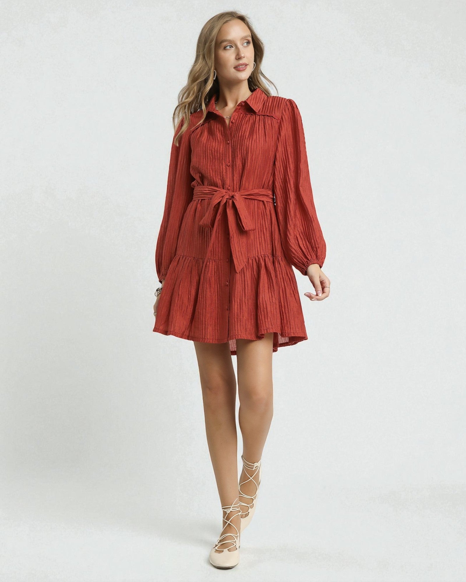 Woman wearing a red dress with long sleeves and a belt on a white background