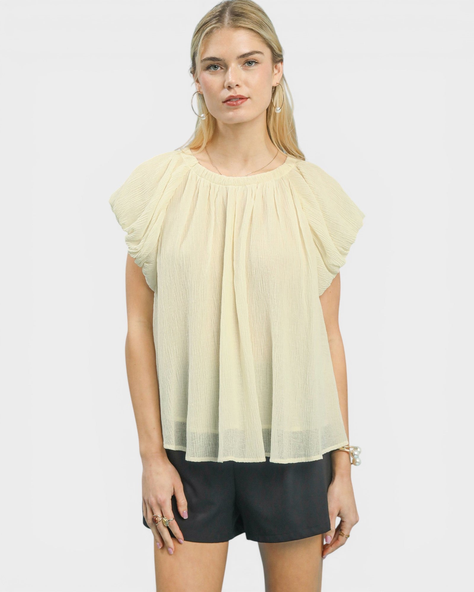 Woman wearing a light yellow blouse with short sleeves on a white background