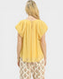 Woman wearing a yellow top and floral pants on a white background