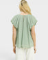 Woman wearing a light green blouse with ruffled sleeves on a white background