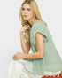 Woman wearing a light green blouse sitting on a chair with a white background