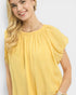 Woman wearing a yellow blouse with a plain background