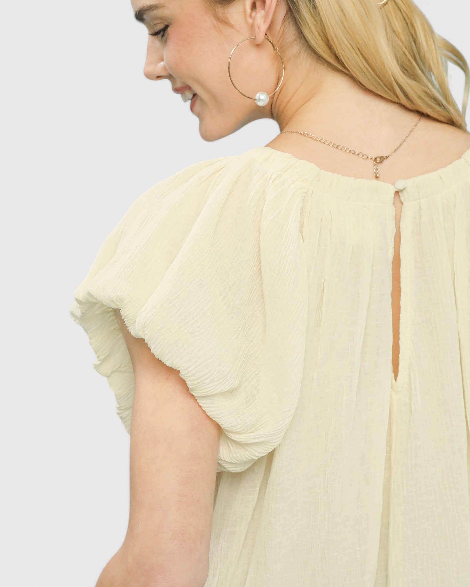 Woman wearing a light yellow blouse with a plain background