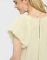Woman wearing a light yellow blouse with a plain background