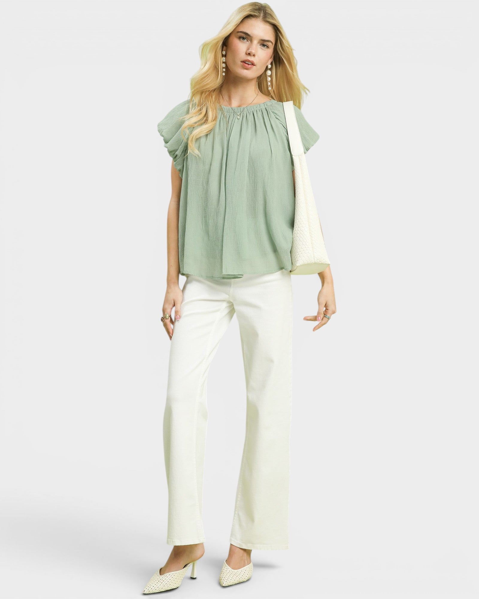 Woman wearing a green blouse and white pants on a white background