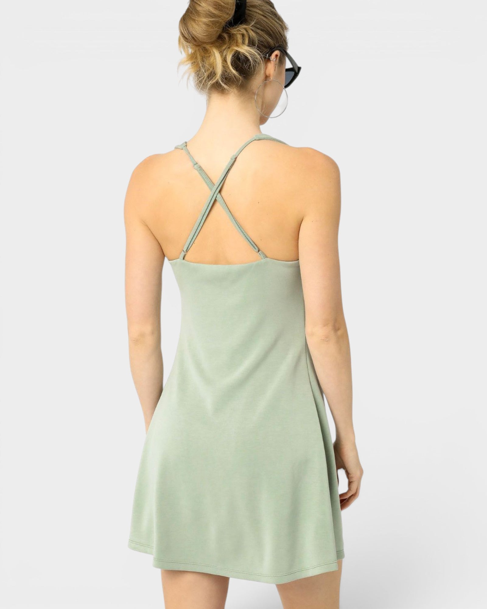 Woman wearing a light green dress with thin straps on a white background