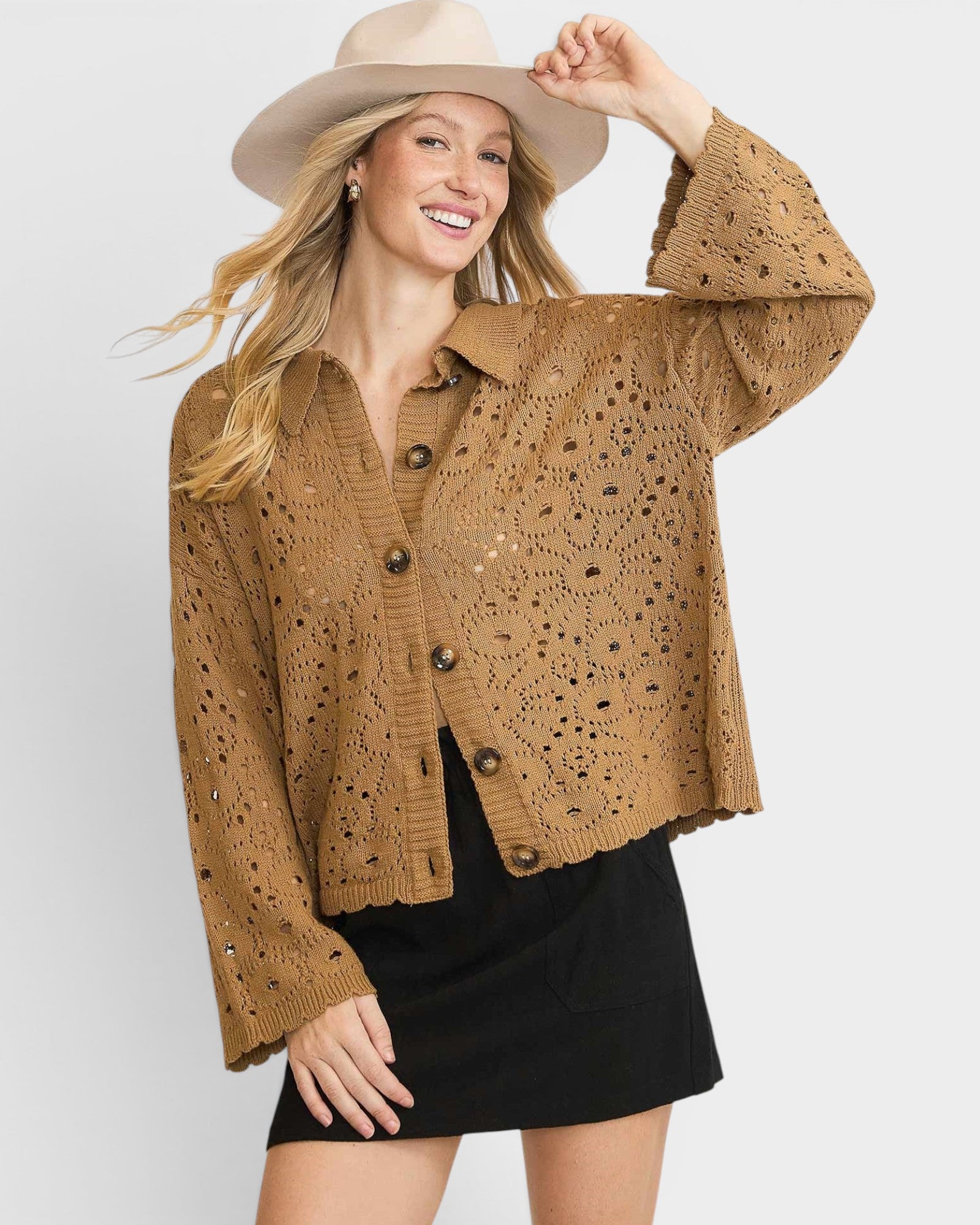 Woman wearing a brown crochet jacket and beige hat on a white background