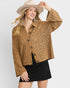 Woman wearing a brown crochet jacket and beige hat on a white background