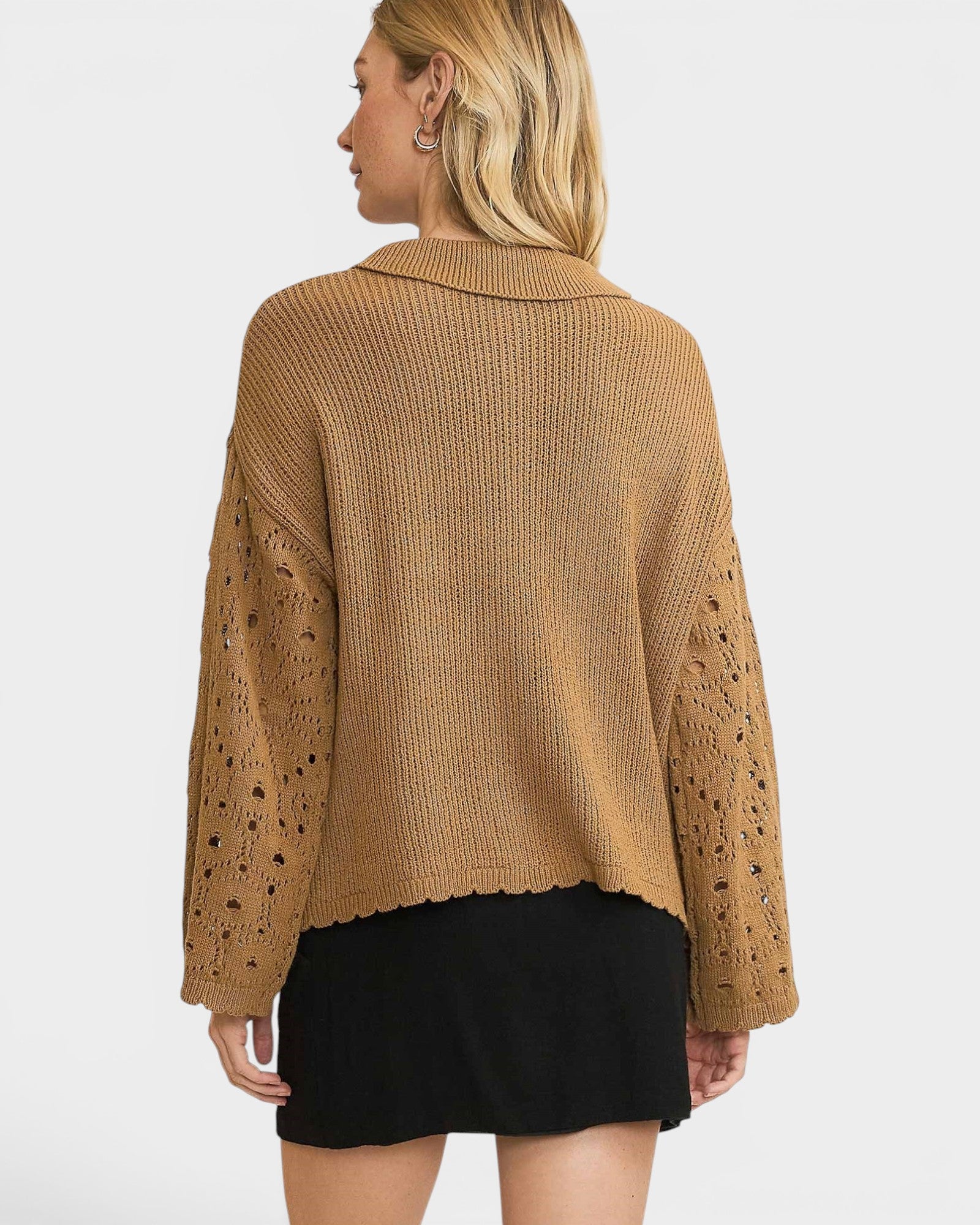 Person wearing a brown knitted sweater with cut-out sleeves on a white background
