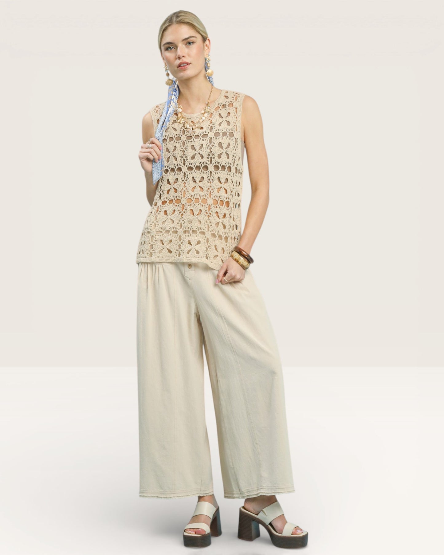 Woman wearing a beige sleeveless top and wide-leg pants on a white background