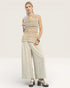 Woman wearing a beige sleeveless top and wide-leg pants on a white background