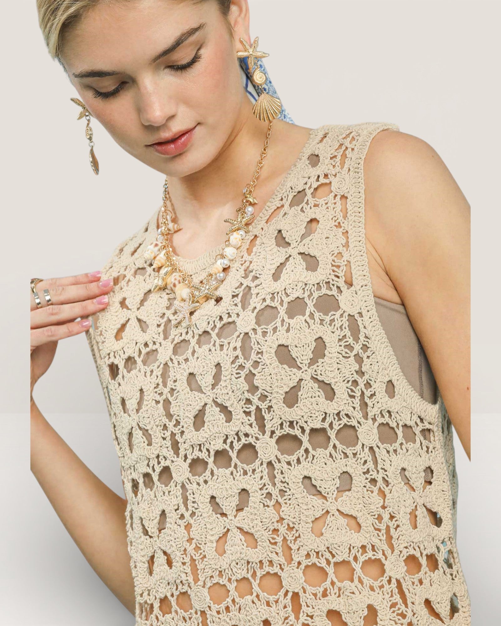 Woman wearing a beige lace top against a plain background