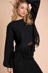 Woman wearing a black fringe sweater against a beige background
