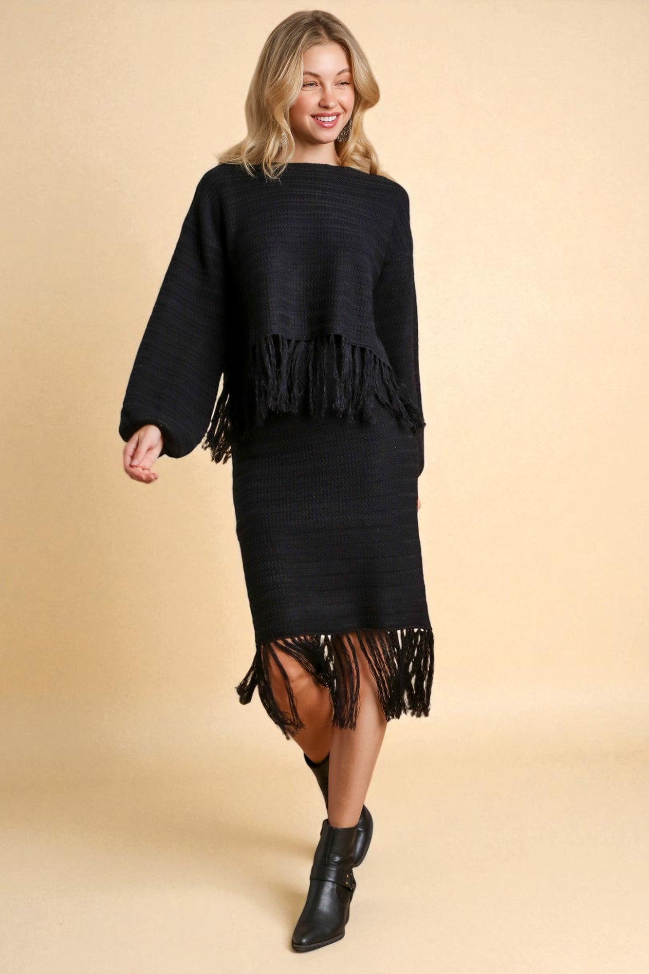 Woman wearing a black fringe sweater and skirt set on a beige background