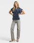 Woman wearing a blue patterned blouse and gray pants on a white background