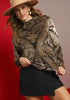 Woman wearing a patterned top and black skirt with a beige hat against a red background