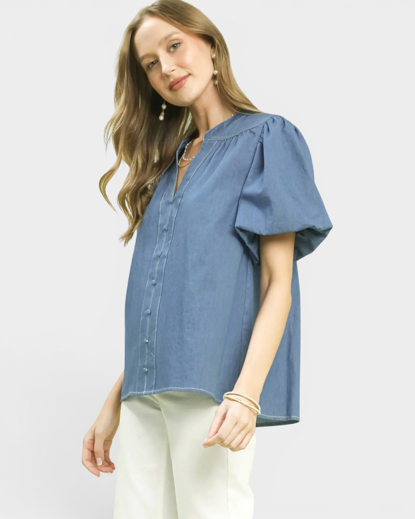 Woman wearing a blue blouse with puff sleeves on a white background