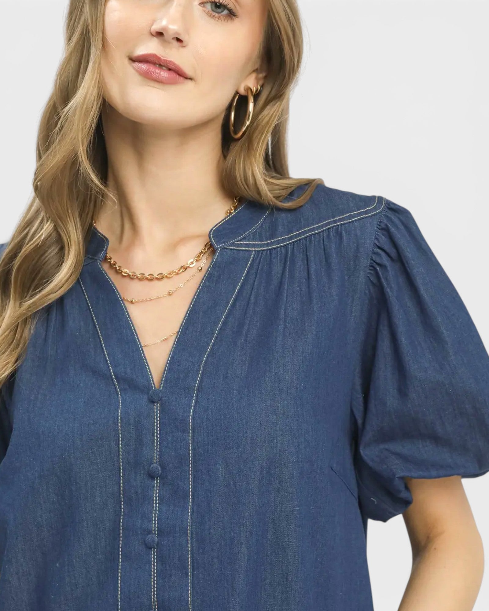 Woman wearing a blue denim dress with a plain background