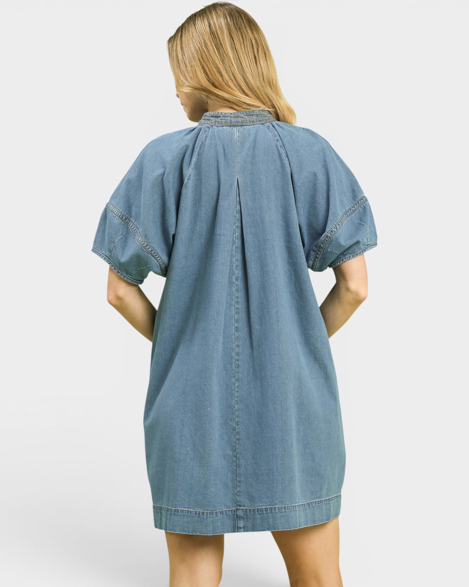 Blue denim dress worn by a person on a white background